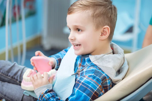 Niño muy feliz después de que el médico en la clínica, sosteniendo una mandíbula dental en sus manos y tener una hermosa sonrisa blanca. Copiar espacio —  Fotos de Stock