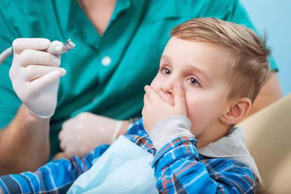 Inspección dental se está dando a un niño pequeño rodeado por el dentista y su asistente, y tiene miedo al médico y la máquina — Foto de Stock