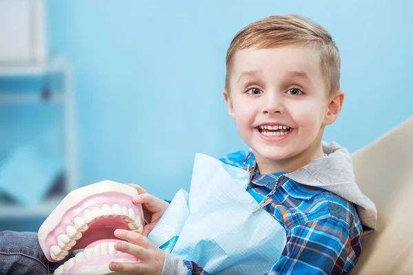 Niño muy feliz después de que el médico en la clínica, sosteniendo una mandíbula dental en sus manos y tener una hermosa sonrisa blanca. Copiar espacio —  Fotos de Stock