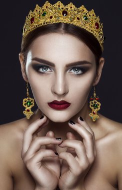 Güzel bir kadın modeli ile profesyonel makyaj, mücevher. Altın taç. Kırmızı ruj.