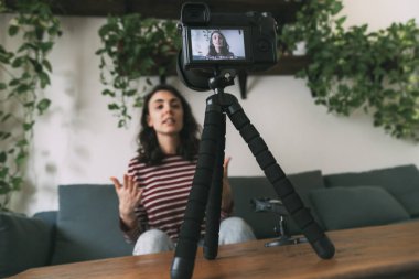 Kız evdeki blogu için dijital kamerayla kendini kaydediyor. Kameraya seçici odaklanma. Video günlüğü kavramı