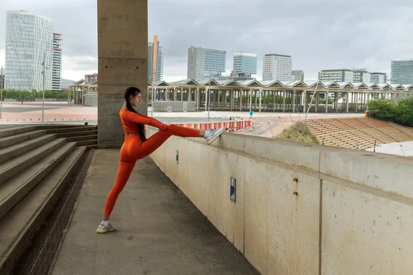 Young female athlete stretching leg, hamstrings, before jogging in the city. Caucasian woman morning workout routine. Sports concept. Active Healthy lifestyle concept. Copy space.