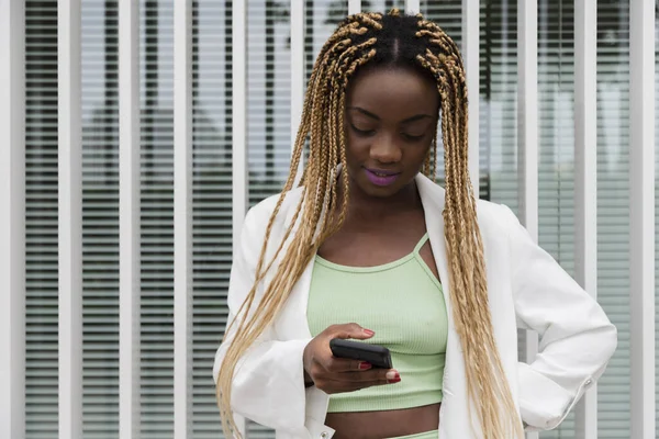 Leende Afroamerikansk Kvinna Med Blonda Flätor Sms Vän Med Mobiltelefon — Stockfoto