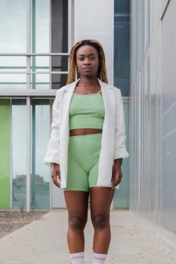 Kentteki kameraya bakan uzun sarı örgülü Afro-Amerikan kadının portresi..