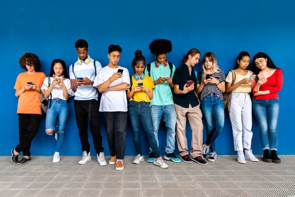 Een Groep Multiraciale Tienerscholieren Leunend Tegen Een Blauwe Muur Kijkend — Stockfoto