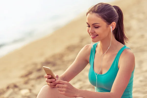 Sportmädchen mit Gadget am Strand — Stockfoto