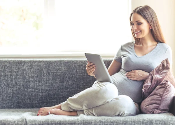 Donna incinta con gadget a casa — Foto Stock