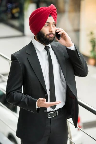 Un hombre con turbante rojo y camisa azul.