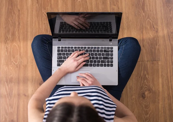 Ansicht von oben: Frau benutzt Laptop, während sie zu Hause auf dem Boden sitzt. — Stockfoto