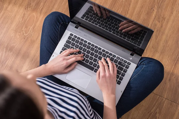 Vista superior de la mujer está utilizando el ordenador portátil mientras está sentado en el suelo en casa . — Foto de Stock