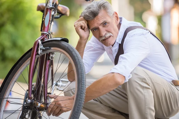 老人正在街上修理自行车 看着照相机 — 图库照片