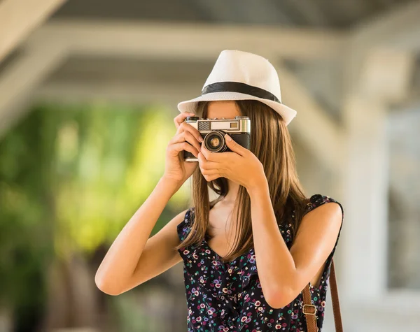 在帽子的年轻美丽的妇女正在拍摄与老式相机 户外图片 — 图库照片