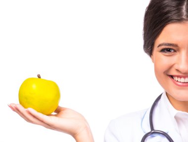 Beyaz önlük beyaz bir arka plan üzerinde izole bir elma tutan genç güzel kadın doktor portresi