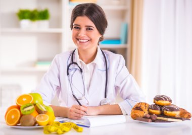 Bir yan ve diğer taraftan fast food meyve ile beyaz paltolu bir genç güzel kadın doktor portresi