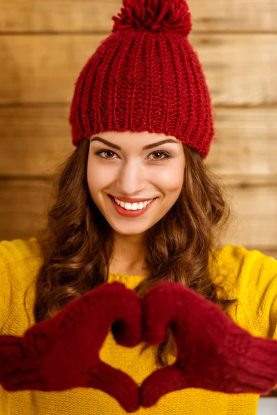 一个美丽的年轻女孩在木墙背景上戴着帽子和手套的肖像 — 图库照片