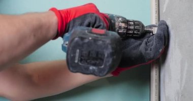 Tesisatçı elektrik tornavidayı kullanarak su tedarik boruları kuruyor ve boruları duvara tamir ediyor..