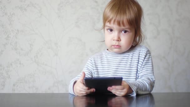 Lustigt barn som håller i en tablett och knackar på surfplattan. Kid och digital utrustning. — Stockvideo