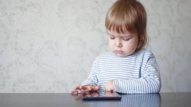 Peuter met behulp van digitale tablet. Baby kind kijkt naar het scherm van het digitale apparaat en tikt op het scherm. Gadget verslaving van kinderen — Stockvideo