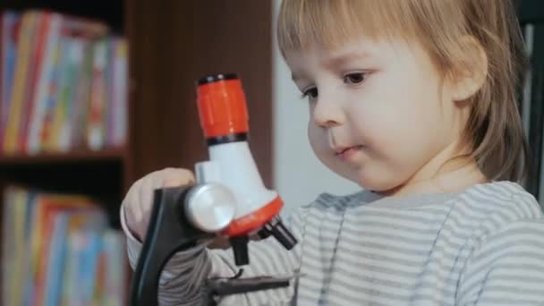 Kind en een microscoop. Peuter speelt met een kind dat speelgoed ontwikkelt. Cognitief educatief speelgoed voor kinderen. — Stockvideo