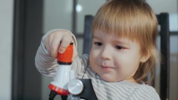 Toddler boy of 2-3 years old playing with a toy microscope. A child repairing a broken toy. — Stockvideo