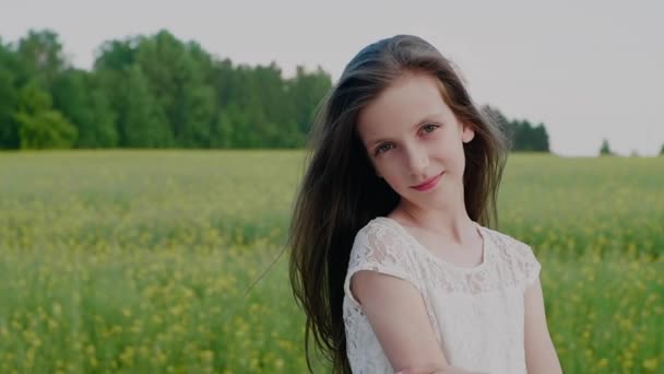 Retrato de una joven niña en edad escolar caucásica sobre un fondo borroso de la naturaleza. Niño en la naturaleza. — Vídeos de Stock