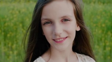 Kafkasyalı gülümseyen okul çağındaki genç bir kızın fotoğrafı bulanık doğa arka planına karşı kameraya bakıyor. Doğadaki çocuk.