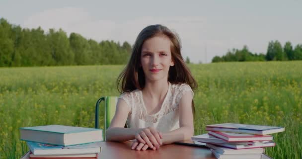 Альтернативна освіта. Шкільний вік дитина сидить за столом з книгами, оточеними природою . — стокове відео