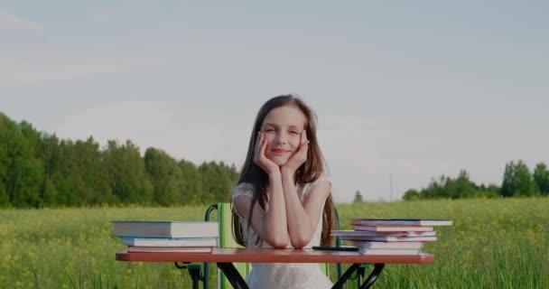 Oktatás a világjárvány idején. Alternatív oktatás. Egy iskolás lány ül az asztalnál, körülvéve természettel. — Stock videók