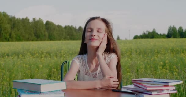 E 'ora di tornare a scuola. Una ragazza felice e sorridente in età scolare su una scrivania con dei libri — Video Stock