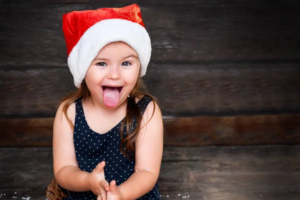 Natal Retrato Criança Santa Chapéu Mostra Língua Fundo Madeira — Fotografia de Stock