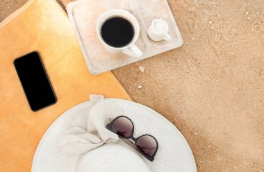 Plajda havlunun üzerindeki şapkalar. Çocuklar ve kadın şapkaları turuncu bir havluyla kumların üzerinde.