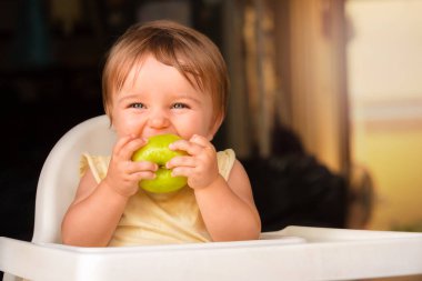 Yeşil elmalı bebek. Çocuk bir elma ısırır ve güler.