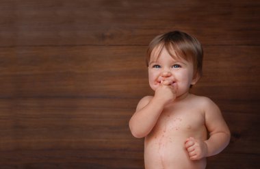 Bebek ahşap arka planda böğürtlen yiyor. Çocuk kırmızı böğürtlen yer, böğürtlenin suyu mideyi kirletir..