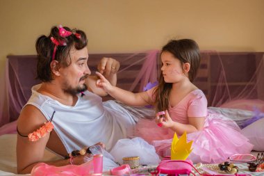 Baba ve kızı birlikte oynuyorlar. Bir çocuk bir erkek için makyaj yapar. Bale elbiseli kız, babamın yüzüne pullar yapıştırıyor.