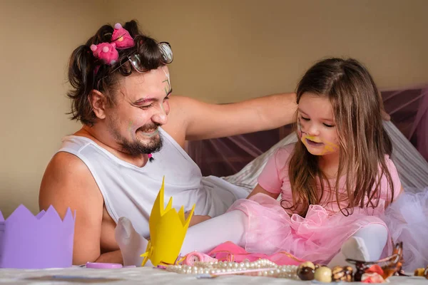 Baba ve kızı birlikte gülüyorlar. Çocuk adamı süsledi..