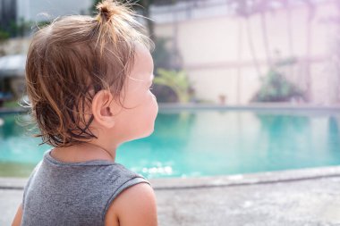 Bebek sırt üstü durur ve havuza bakar.