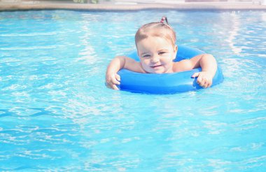 Smiling baby in the pool. Child learns to swim in a swimming circle