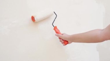 El, duvarı beyaz bir boyayla boyuyor.