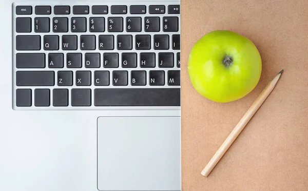 Work space background. An apple with a notebook on the keyboard is close