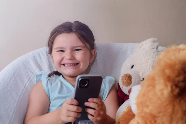 Ребёнок Сидит Кресле Игрушками Медведями Играет Телефону — стоковое фото