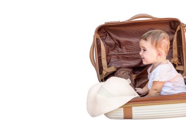 Güzel bebek bavulda oturuyor ve beyaz arka planda izole edilmiş fotokopi alanına bakıyor.