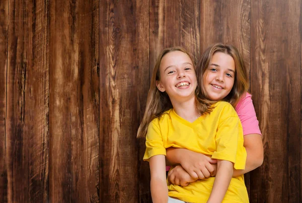 Dvě Dívky Sestry Stojí Pohromadě Objímají Dřevěném Pozadí — Stock fotografie