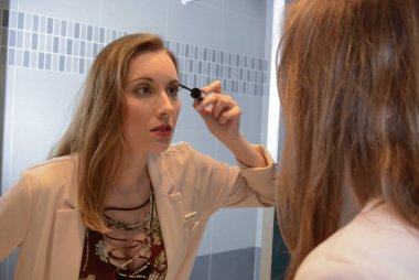 Banyoda kirpiklerine makyaj yapan bir kadın..