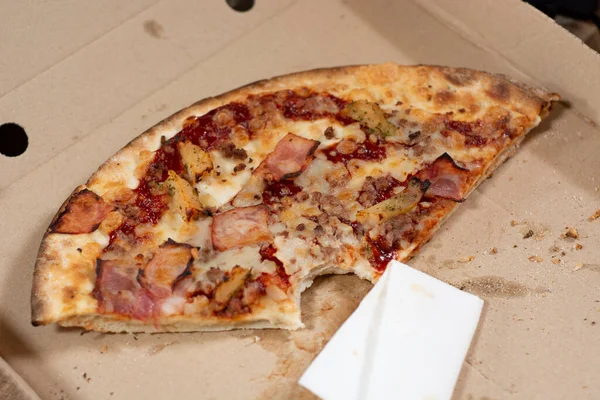 Akşam yemeğinden arta kalanlar, karton kutuda çiğnenmiş bir dilim pizza..