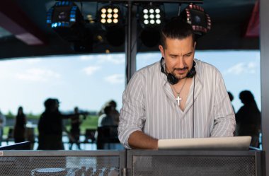Açık hava etkinliği sırasında bilgisayarda şarkı arayan, kulaklık takan Latin DJ..