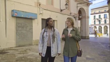 İki farklı genç bayan arkadaş Avrupa 'nın bu güzel caddesinde yürüyor ve sohbet ediyorlar.