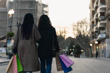 İki Afrikalı arkadaş alışveriş sonrası kucaklaşarak yürüyorlar..