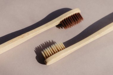 Bej arka planda zıt gölgelerle biyolojik olarak çözünebilen iki bambu diş fırçası.