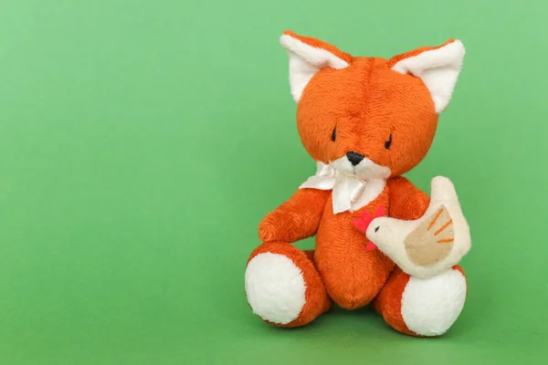 Soft toy ginger fox with chicken on a green background