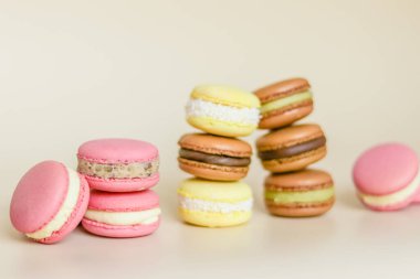 Açık arkaplanda yığınla renkli badem kurabiyesi var.